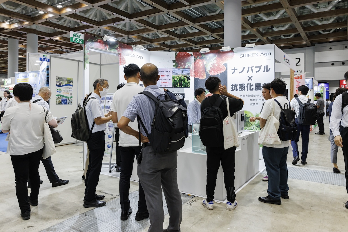 ナノバブル水素水生成機のブースに立ち止まる人々