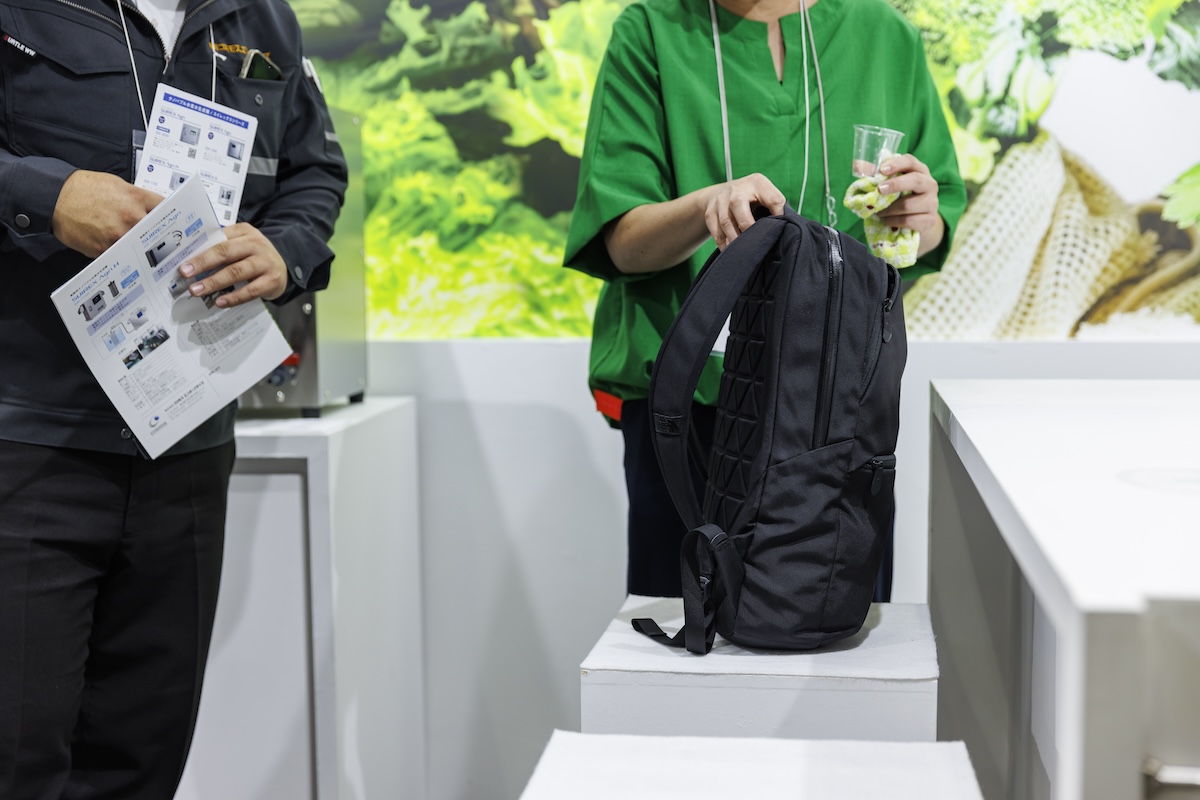 箱椅子に荷物を置いて話を聞く来場者